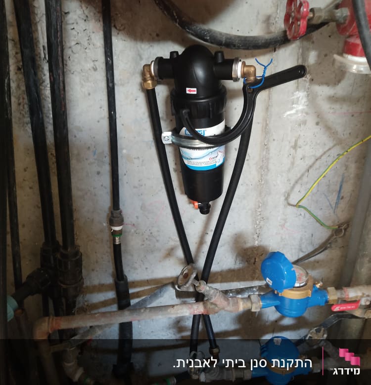 מסנן מים מותקן על קיר עם צינורות וחיבורים